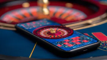 একজন পুরুষ তার ল্যাপটপে জয়ের মুহূর্ত উদযাপন করছেন, চারপাশে ভাসছে গেমিং আইকন—যা 4777BETT গেমসের উত্তেজনাকে প্রকাশ করে।